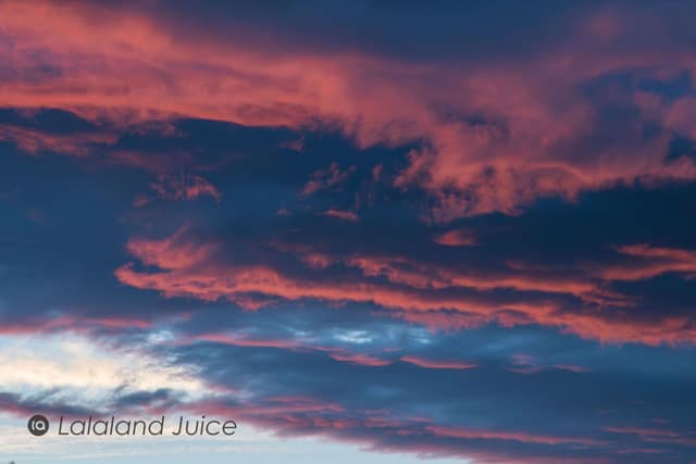 A soft pink-and-blue twilight sky, the day's last light going down — the Lalaland Juice mark set within.