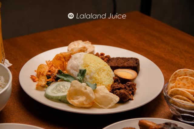 A plate of nasi padang — rice with rendang, egg, tempeh, cucumber and keropok — the economy-rice spread.