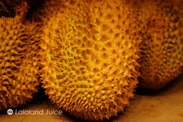 A close-up of golden, spiky durian shells at a market — durian, the fruit Singapore calls the 'heaty' king.